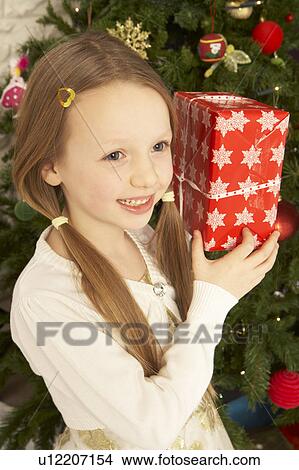 Young Girl Holding Christmas Present In Front Of Christmas Tree View Large Photo Image Picture - Young Girl Holding Christmas Present In Front Of Christmas Tree. Fotosearch