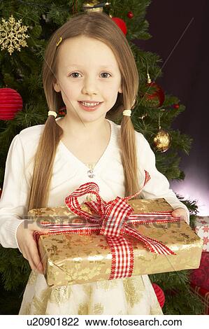 Young Girl Holding Christmas Present In Front Of Christmas Tree View Large Photo Image Stock Image - Young Girl Holding Christmas Present In Front Of Christmas Tree. Fotosearch