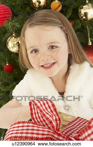Young Girl Holding Gift In Front Of Christmas Tree View Large Photo Image Picture - Young Girl Holding Gift In Front Of Christmas Tree. Fotosearch