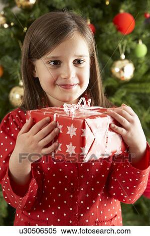 Young Girl Holding Gift In Front Of Christmas Tree View Large Photo Image Stock Photography - Young Girl Holding Gift In Front Of Christmas Tree. Fotosearch