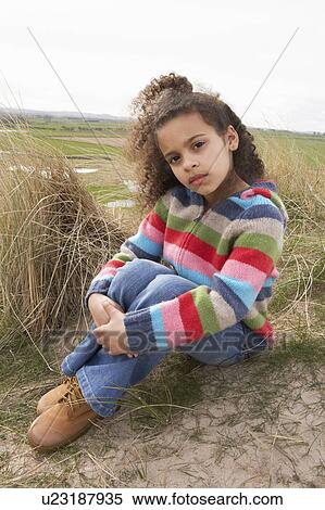 Stock Photography - Young Girl Sitting Amongst Dunes On Winter Beach. Fotosearch