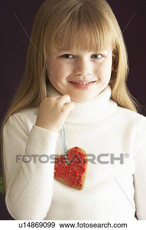 Stock Photo - Young Holding Heart Shaped Cookie In Studio. Fotosearch