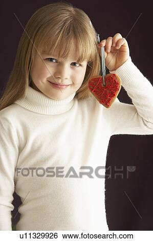 Stock Photograph - Young Holding Heart Shaped Cookie In Studio. Fotosearch