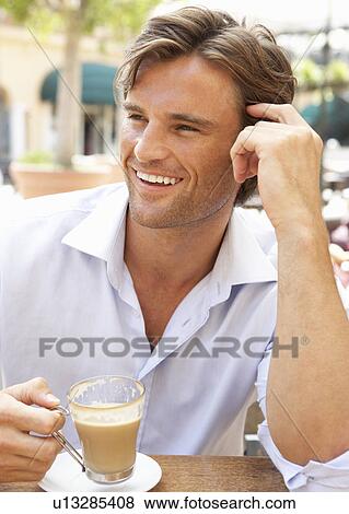 Stock Photo - Young Man Enjoying Cup Of Coffee In Café. Fotosearch