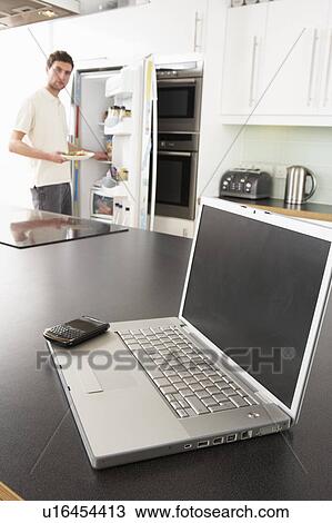Young Man Fixing Snack In Kitchen With Laptop In Modern Kitchen View Large Photo Image Stock Image - Young Man Fixing Snack In Kitchen With Laptop In Modern Kitchen . Fotosearch