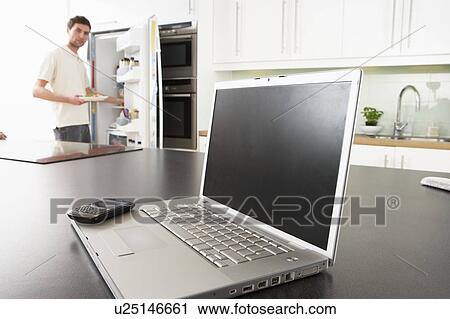 Young Man Fixing Snack In Kitchen With Laptop In Modern Kitchen View Large Photo Image Stock Image - Young Man Fixing Snack In Kitchen With Laptop In Modern Kitchen . Fotosearch