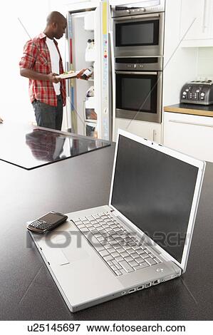 Young Man Fixing Snack In Kitchen With Laptop In Modern Kitchen View Large Photo Image Stock Photo - Young Man Fixing Snack In Kitchen With Laptop In Modern Kitchen . Fotosearch