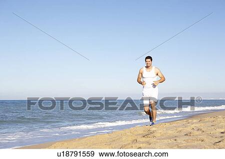 Stock Photo - Young Man In Fitness Clothing Running Along Beach. Fotosearch