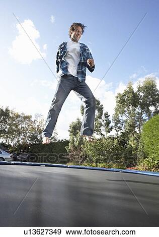 Stock Photo - Young Man Jumping On Trampoline Caught In Mid Air. Fotosearch