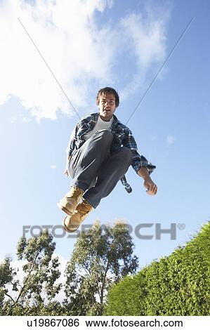 Stock Photograph - Young Man Jumping On Trampoline Caught In Mid Air. Fotosearch