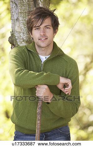 Stock Photo - Young Man Outdoors Walking In Autumn Woodland Holding Walking Stick. Fotosearch