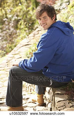 Stock Photo - Young Man Relaxing In Autumn Garden. Fotosearch