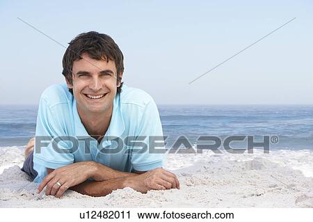 Stock Image - Young Man Relaxing On Sandy Beach. Fotosearch