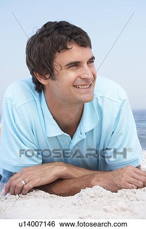 Stock Photograph - Young Man Relaxing On Sandy Beach. Fotosearch
