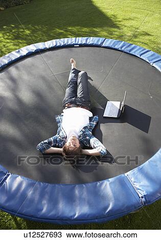 Young Man Relaxing On Trampoline With Laptop View Large Photo Image Stock Image - Young Man Relaxing On Trampoline With Laptop. Fotosearch