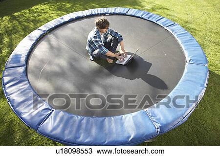 Young Man Relaxing On Trampoline With Laptop View Large Photo Image Stock Image - Young Man Relaxing On Trampoline With Laptop. Fotosearch