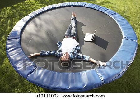 Young Man Relaxing On Trampoline With Laptop View Large Photo Image Stock Image - Young Man Relaxing On Trampoline With Laptop. Fotosearch