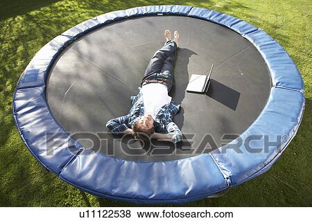 Young Man Relaxing On Trampoline With Laptop View Large Photo Image Stock Photo - Young Man Relaxing On Trampoline With Laptop. Fotosearch