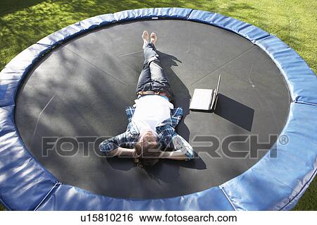 Young Man Relaxing On Trampoline With Laptop View Large Photo Image Stock Photograph - Young Man Relaxing On Trampoline With Laptop. Fotosearch