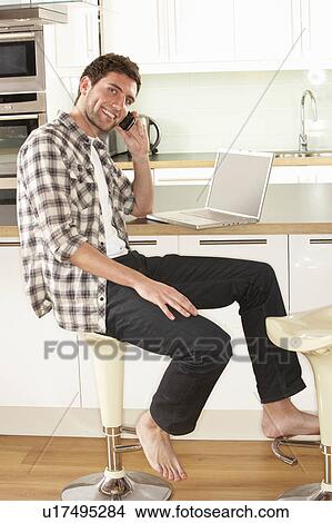 Young Man Relaxing Sitting In Kitchen Talking On Phone View Large Photo Image Picture - Young Man Relaxing Sitting In Kitchen Talking On Phone. Fotosearch