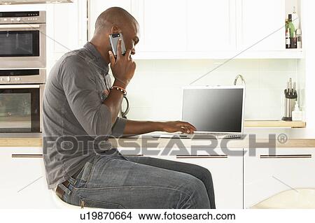 Young Man Relaxing Sitting In Kitchen Talking On Phone View Large Photo Image Picture - Young Man Relaxing Sitting In Kitchen Talking On Phone. Fotosearch