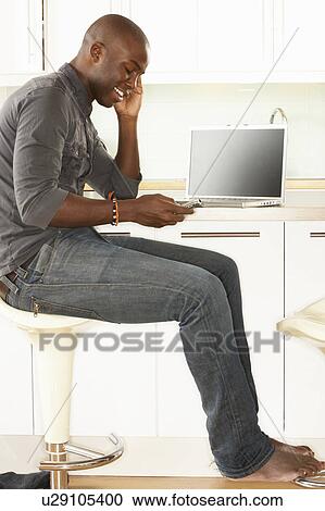 Young Man Relaxing Sitting In Kitchen Talking On Phone View Large Photo Image Stock Image - Young Man Relaxing Sitting In Kitchen Talking On Phone. Fotosearch