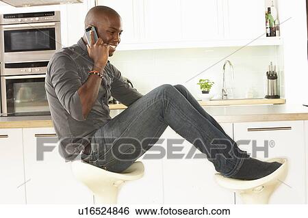Young Man Relaxing Sitting In Kitchen Talking On Phone View Large Photo Image Stock Photograph - Young Man Relaxing Sitting In Kitchen Talking On Phone. Fotosearch