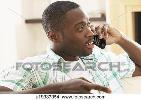 Picture - Young Man Relaxing Sitting On Sofa At Home Talking On Phone. Fotosearch
