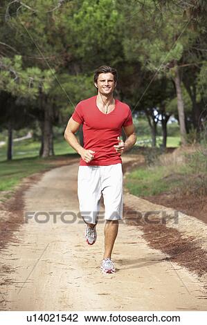 Stock Image - Young man running through park. Fotosearch