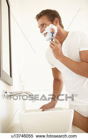 Stock Photography - Young Man Shaving In Bathroom Mirror. Fotosearch
