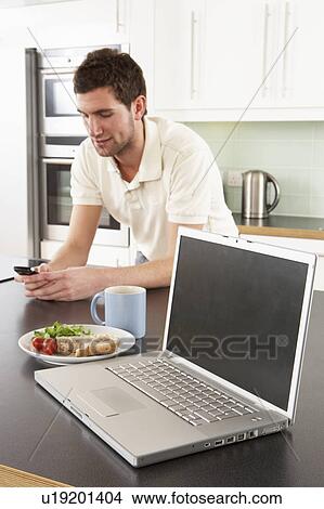 Picture - Young Man With Laptop In Modern Kitchen About To Eat Meal. Fotosearch
