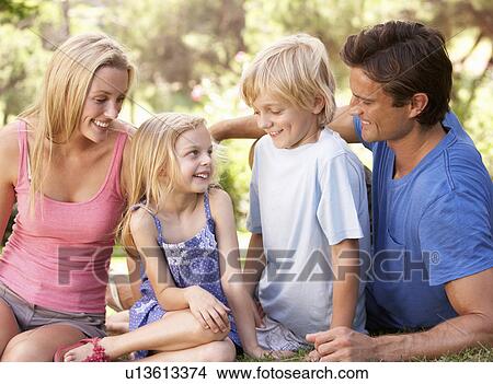 Young parents with children talking in a park View Large Photo Image Picture - Young parents with children talking in a park. Fotosearch