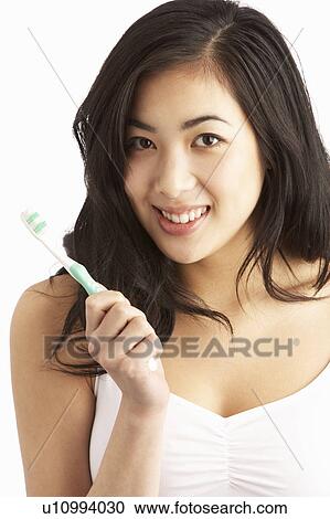 Stock Image - Young Woman Brushing Teeth In Studio. Fotosearch