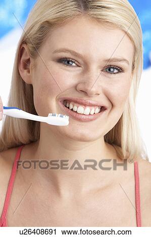 Stock Image - Young Woman Brushing Teeth In Studio. Fotosearch