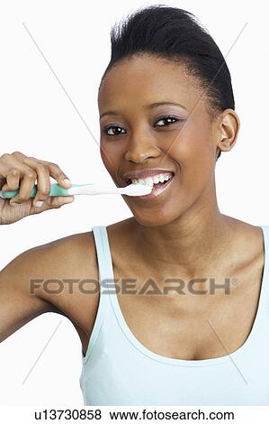 Stock Photo - Young Woman Brushing Teeth In Studio. Fotosearch