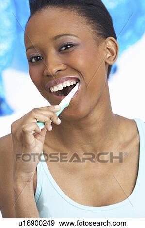 Stock Photo - Young Woman Brushing Teeth In Studio. Fotosearch