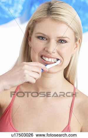 Stock Photograph - Young Woman Brushing Teeth In Studio. Fotosearch