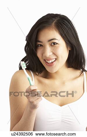 Stock Photograph - Young Woman Brushing Teeth In Studio. Fotosearch