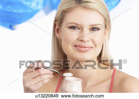 Stock Photo - Young Woman Eating Yoghurt In Studio. Fotosearch