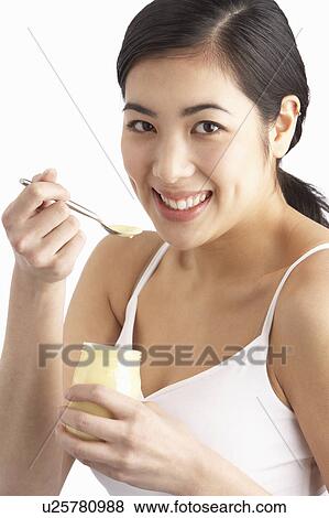 Stock Photo - Young Woman Eating Yoghurt In Studio. Fotosearch