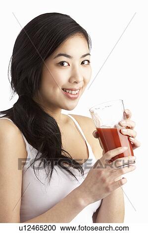 Stock Image - Young Woman Enjoying Healthy Drink In Studio. Fotosearch