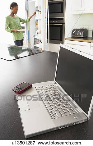 Young Woman Fixing Snack In Kitchen With Laptop In Modern Kitchen View Large Photo Image Stock Photo - Young Woman Fixing Snack In Kitchen With Laptop In Modern Kitchen . Fotosearch