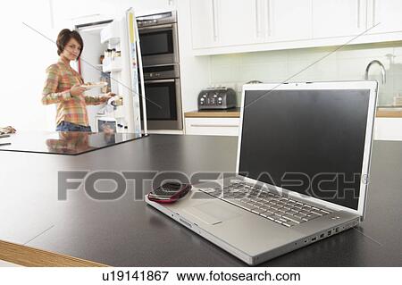 Young Woman Fixing Snack In Kitchen With Laptop In Modern Kitchen View Large Photo Image Stock Photo - Young Woman Fixing Snack In Kitchen With Laptop In Modern Kitchen . Fotosearch