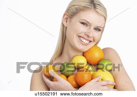 Stock Image - Young Woman Holding Citrus Fruit In Studio. Fotosearch