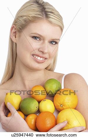 Stock Image - Young Woman Holding Citrus Fruit In Studio. Fotosearch