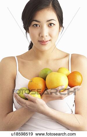 Stock Photo - Young Woman Holding Citrus Fruit In Studio. Fotosearch