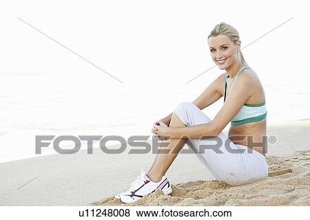 Young Woman In Fitness Clothing Resting After Exercise On Beach View Large Photo Image Stock Photo - Young Woman In Fitness Clothing Resting After Exercise On Beach. Fotosearch
