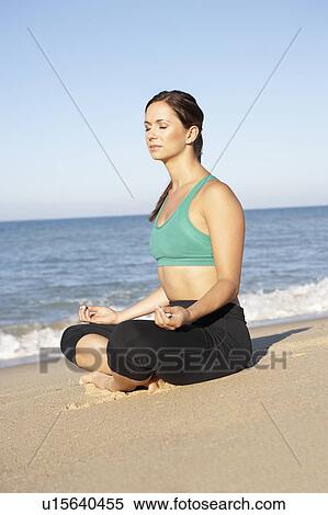Stock Photography - Young Woman In Fitness Clothing Meditating On Beach. Fotosearch