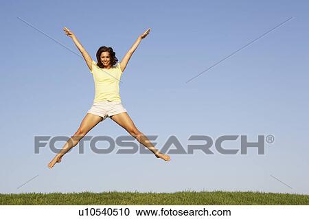 Young woman jumping in air View Large Photo Image Stock Image - Young woman jumping in air. Fotosearch