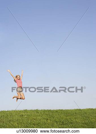 Stock Image - Young woman jumping in air. Fotosearch
